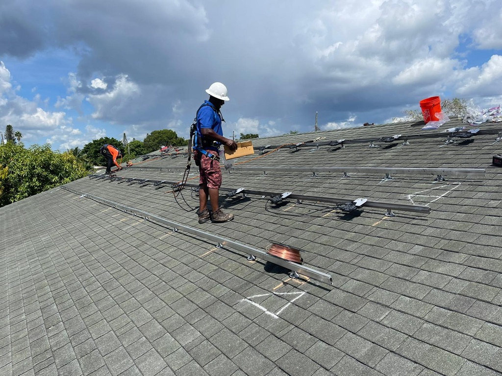 A team of solar panel installers working with EnergyBillTrimmers on a Florida rooftop. Another energy bill cut in half.